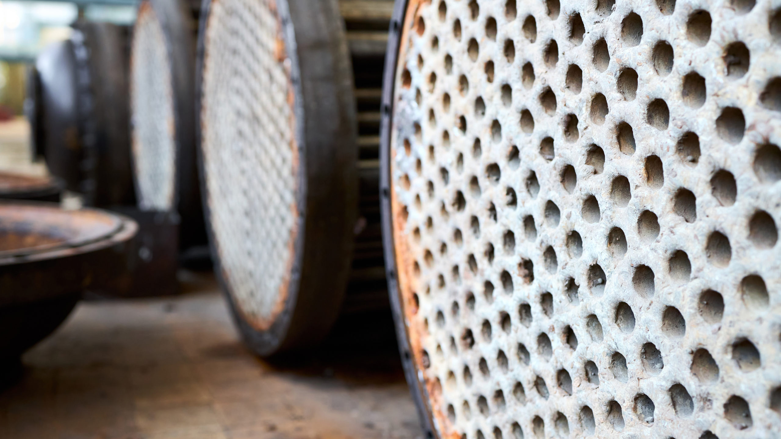 Corrosion, refinery heat exchangers chiller tubes with flange system. Row of Industrial heat exchangers or boilers with covers rusty tube sheet or tube board with deposits and corrosion.